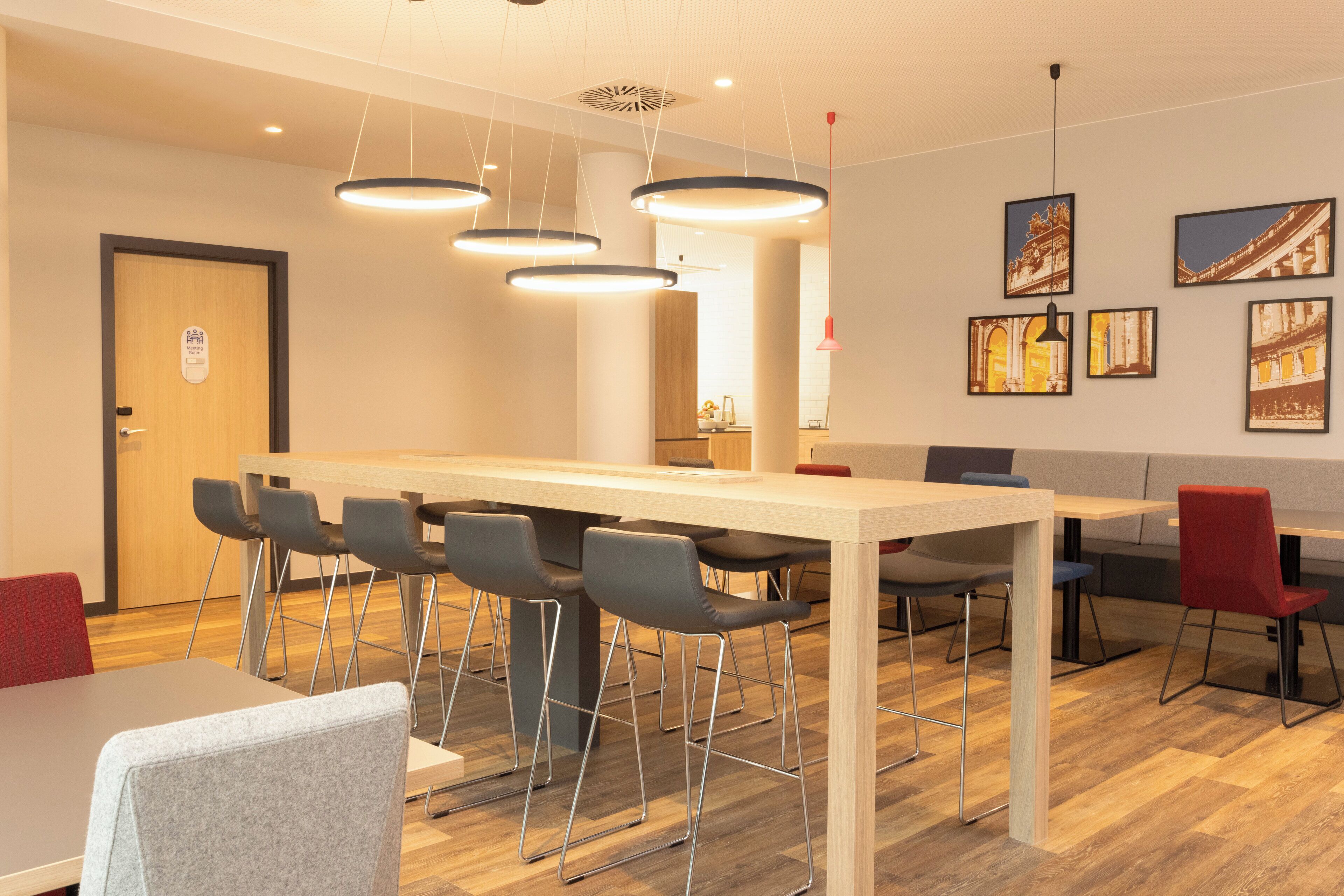 A modern dining area with a long table, multiple chairs, and pendant lighting.