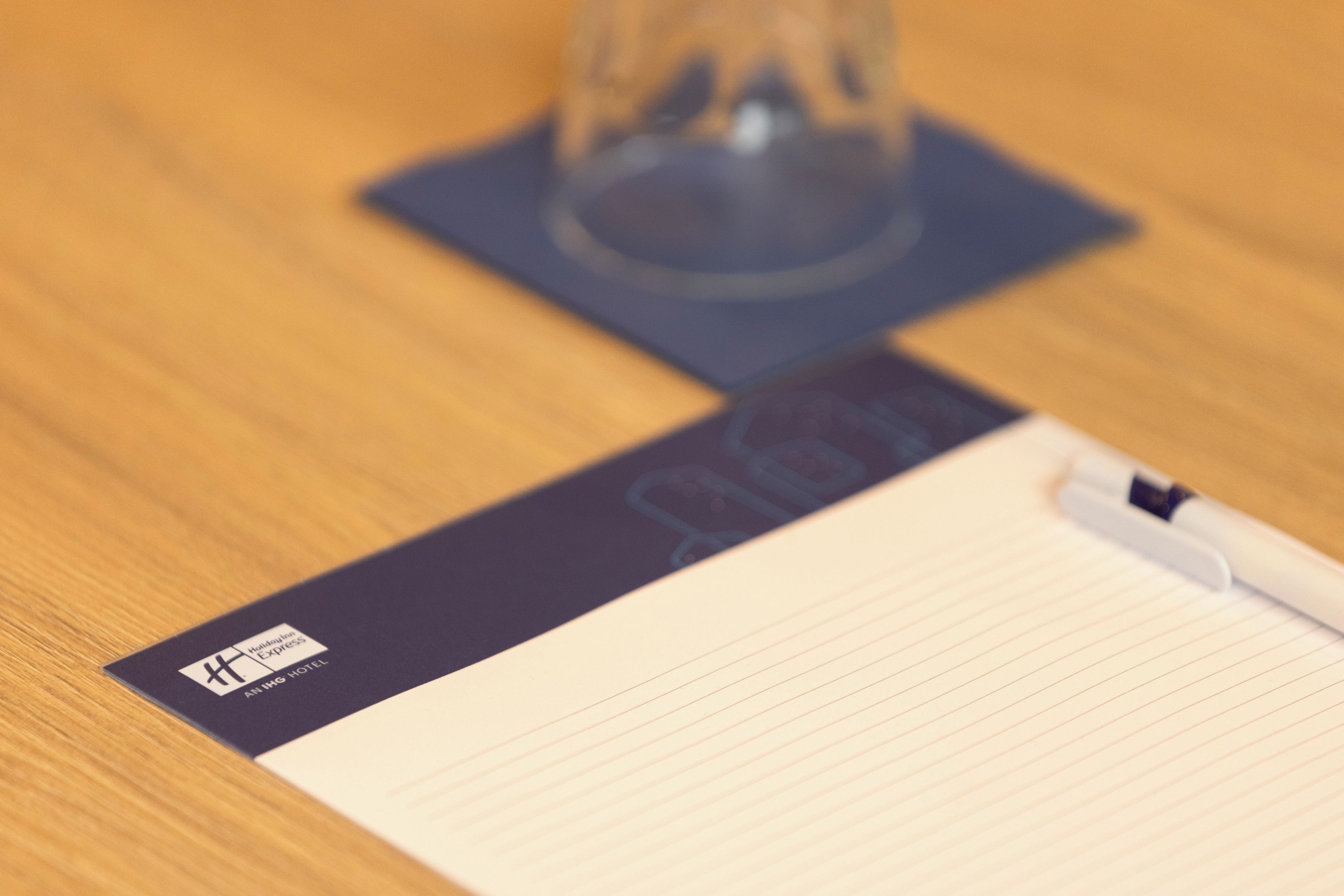 A hotel business card, a notepad, and a pen on a wooden surface.