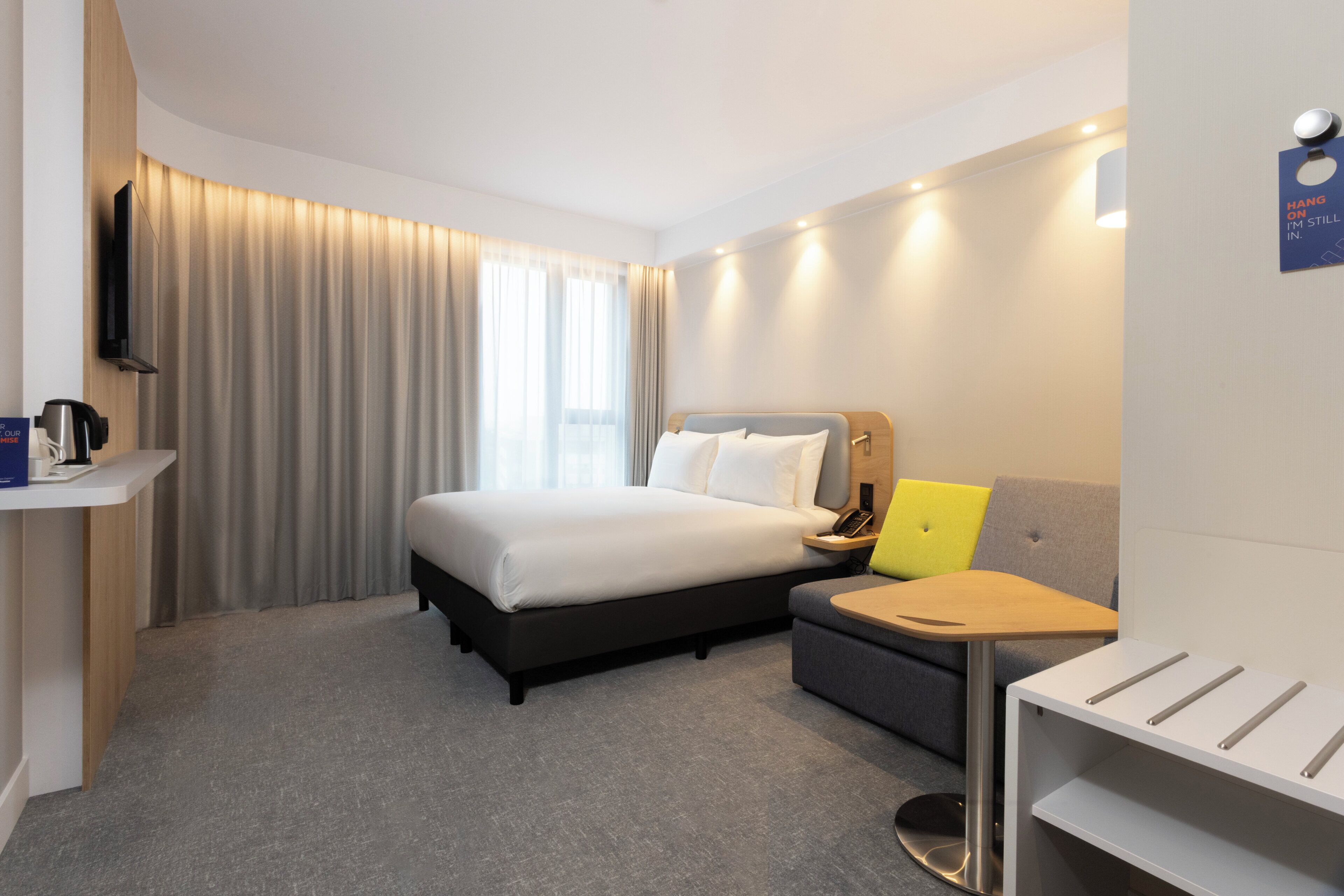 Una habitación de hotel con cama, mesita de noche, escritorio y una silla.