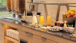 A buffet setup with various food items and condiments. - Holiday Inn Express Brussels Airport by IHG (Machelen)