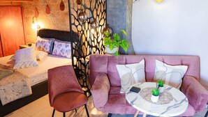 Una habitación acogedora con cama, sofá, sillón y una mesita con plantas.