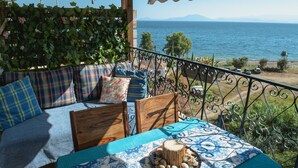 A balcony with a sofa, table, and decorative items, overlooking a coastal view. - Lilly s Seaview Studio (South Pelion)