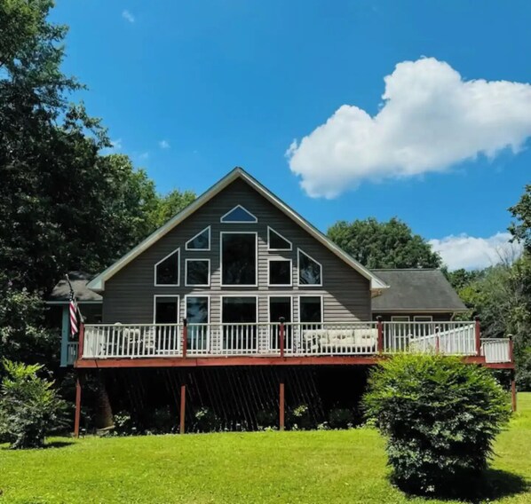 A two-story house with a balcony, surrounded by greenery.