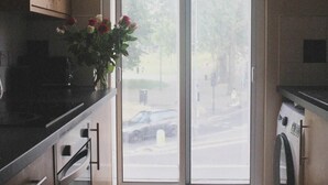 A modern kitchen with a large window, a washing machine, and a vase with flowers on the counter. - London Gem - Chic Apartment Retreat (London)