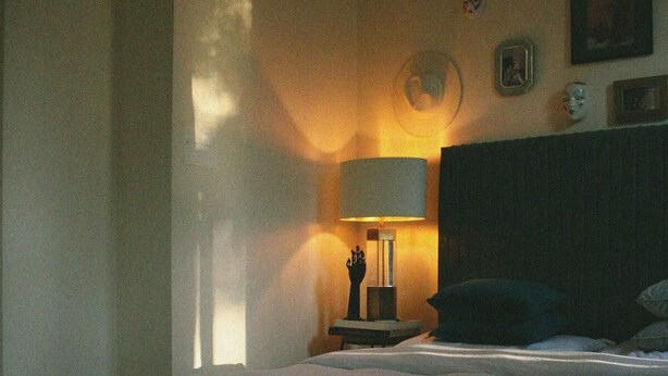 Um quarto com uma cama, uma mesa de cabeceira, uma luminária e um relógio na parede.