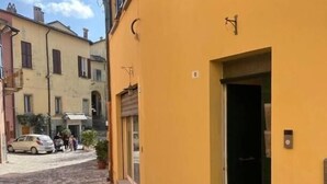 En smal kullerstensgata med en gul byggnad som har en dörr och ett litet fönster.