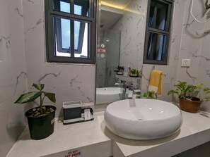 Une salle de bain moderne avec un lavabo rond, un miroir et deux fenêtres.