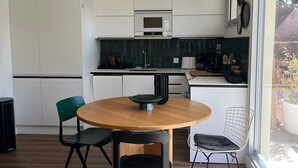 A modern kitchen with white cabinets, a round wooden table, and two chairs.