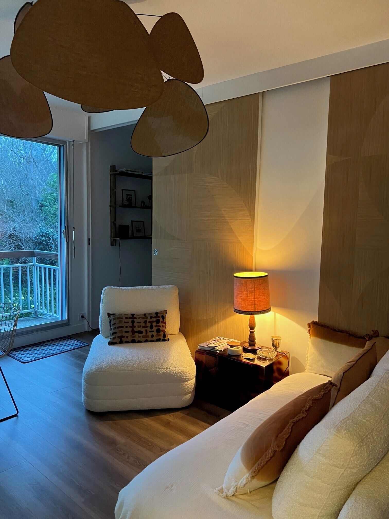 Ein Wohnzimmer mit einer Couch, einer Lampe, einem Sessel und Blick ins Freie.