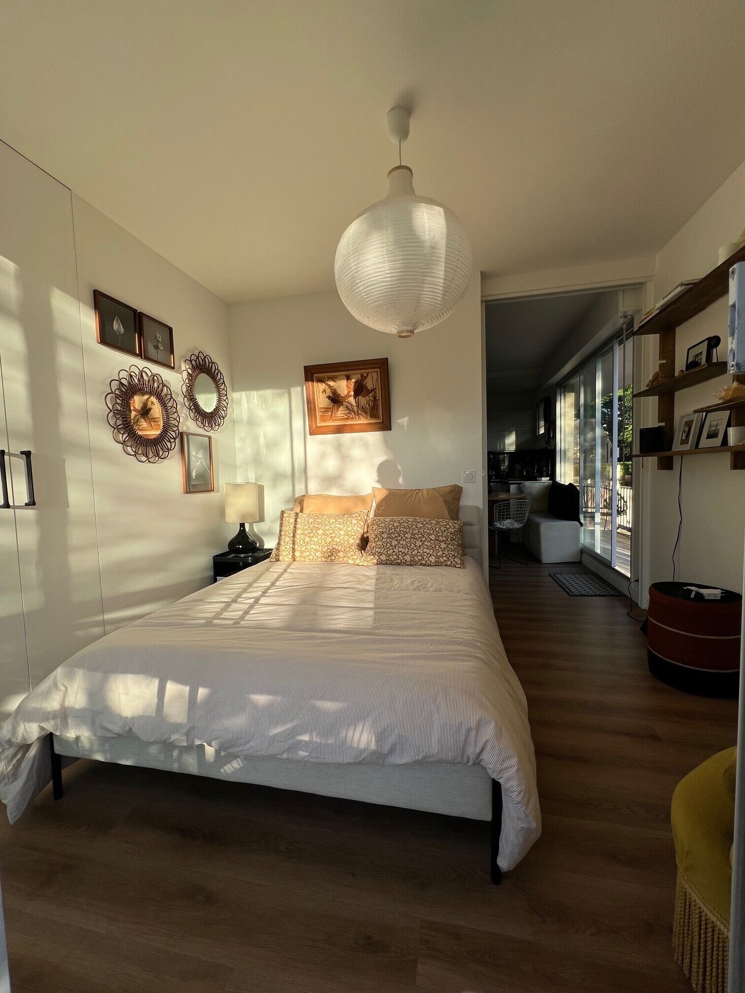 Ein Schlafzimmer mit Bett, Pendelleuchte, Stuhl und Blick ins Freie.