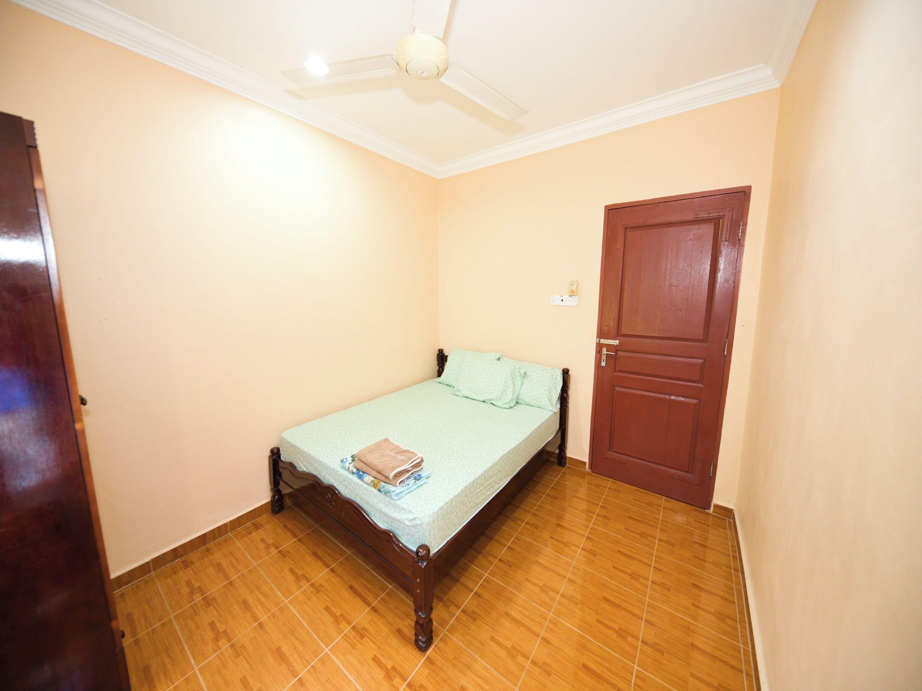 A bedroom with a wooden bed, a ceiling fan, and a door.
