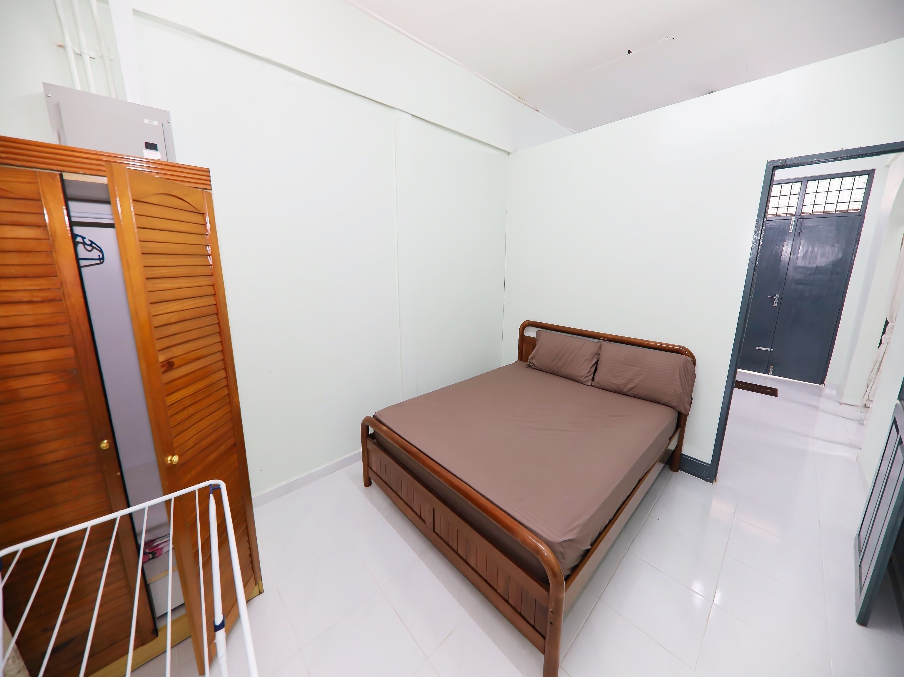 Un dormitorio con estructura de cama de madera, un armario y una puerta.