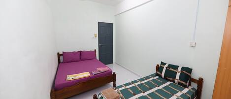 A bedroom with two beds, a ceiling fan, and a door.