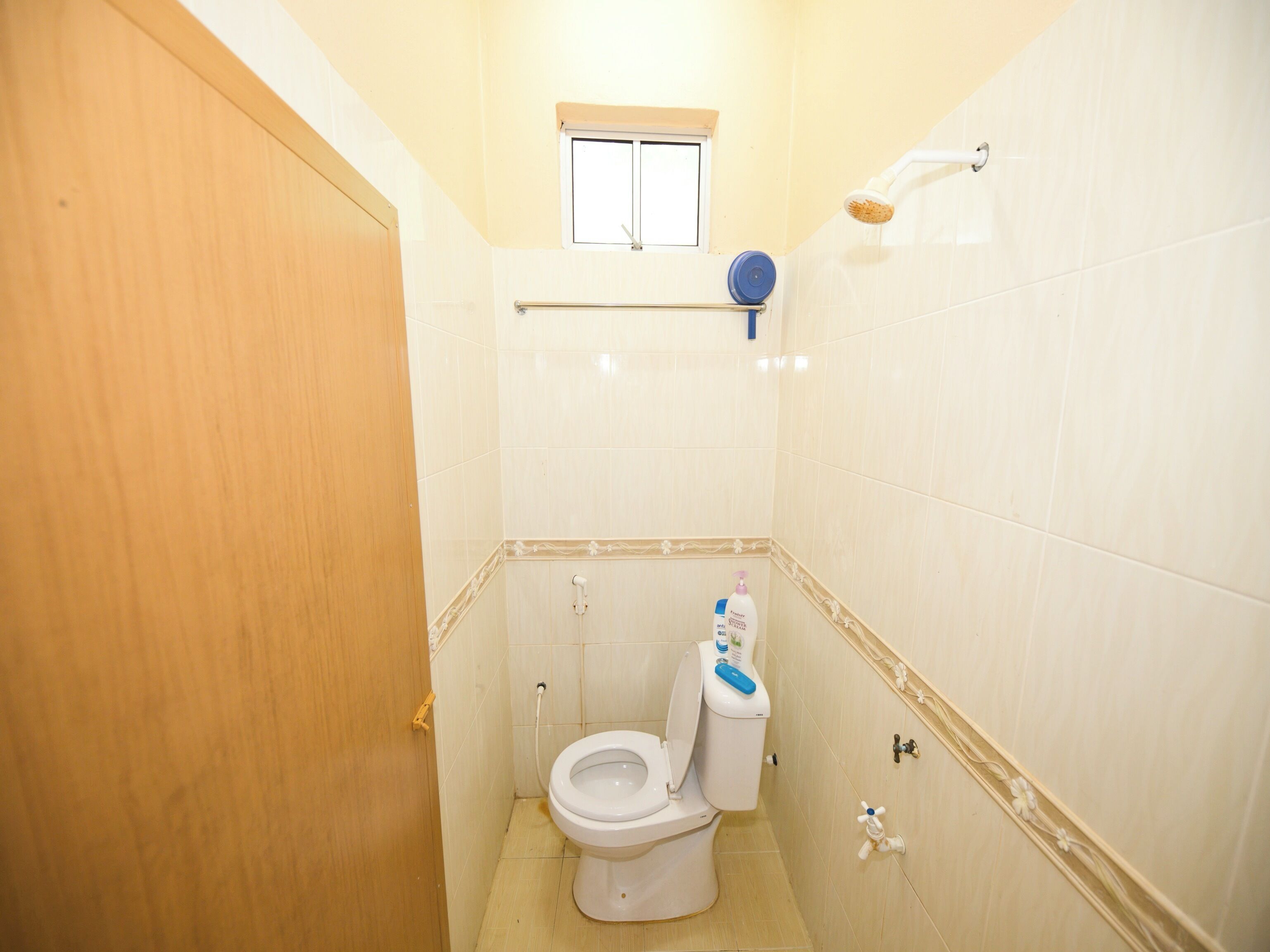 Une petite salle de bain propre, équipée de toilettes, d’une fenêtre et d’une douche.