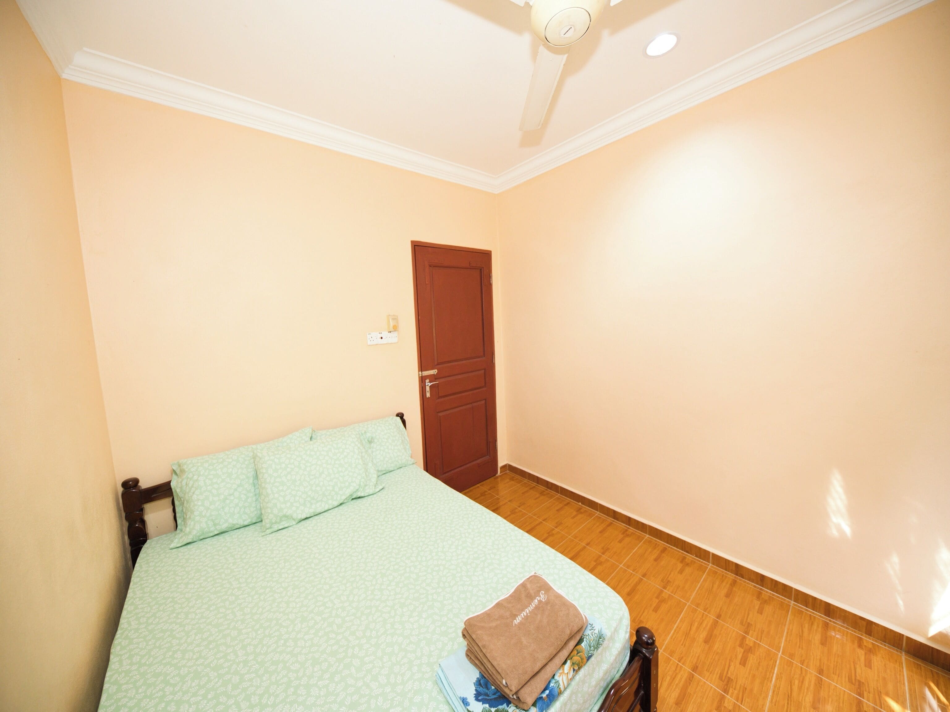 A bedroom with a bed, a door, and a ceiling fan.