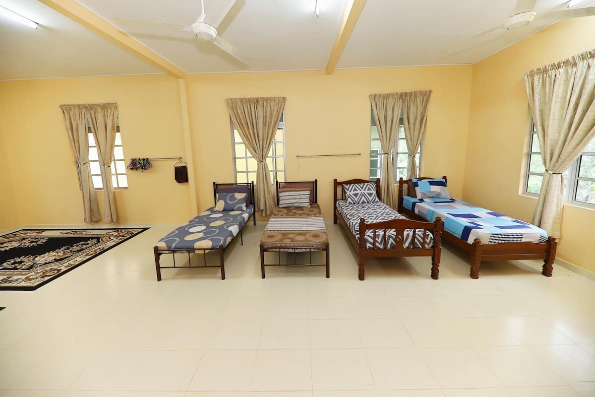 A room with three single beds, a ceiling fan, and a large window with curtains.