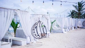 A beachside lounge area with white canopies, hanging chairs, and string lights. - WHITE DECK BEACH RESORT (Lekki)