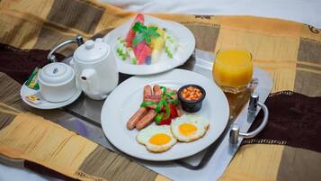Ein Frühstücksbrett mit Eiern, Würstchen, Bohnen und einem Glas Orangensaft.