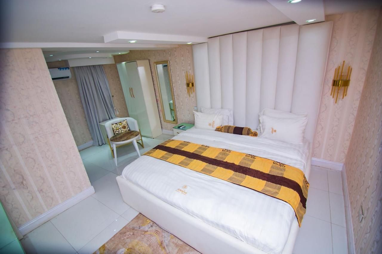 Een hotelkamer met een groot bed, een stoel, een spiegel en een kledingkast.