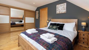 Un dormitorio con una cama grande, un armario de madera, un espejo y obras de arte en la pared.