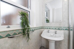 A bathroom with a white sink, a mirror, and a window with a plant. - In the heart of it! S (Stokesley)
