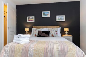 A neatly made bed with a striped blanket, two bedside lamps, and a headboard. - In the heart of it! S (Stokesley)
