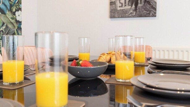 Ein Frühstückstisch gedeckt mit Orangensaftgläsern, Erdbeeren in einer Schale und Croissants.