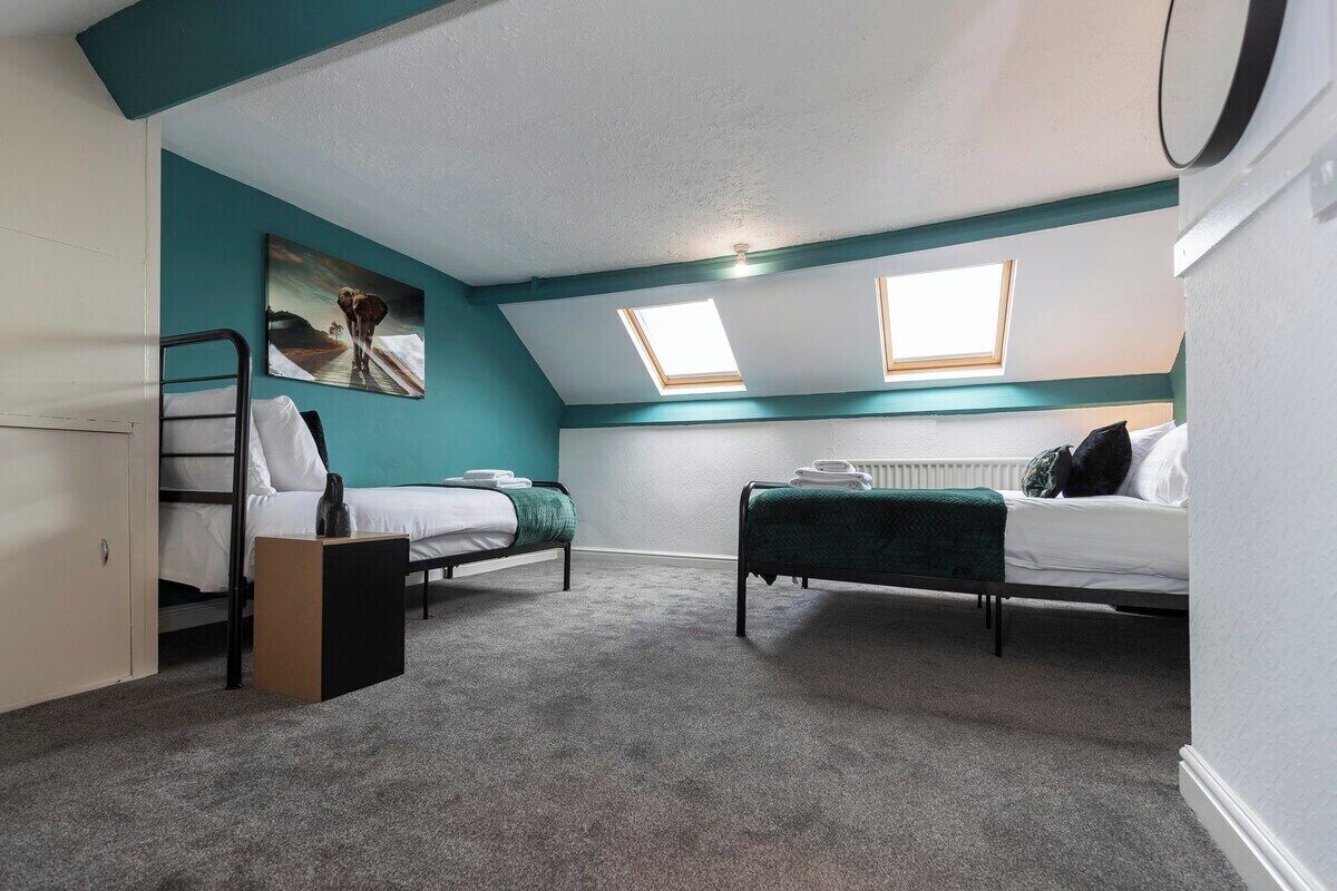 A room with two beds, a radiator, and a skylight.