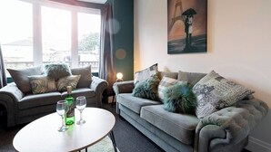 Ein Wohnzimmer mit zwei Sofas, einem Couchtisch und einem Gemälde einer Person mit einem Regenschirm.
