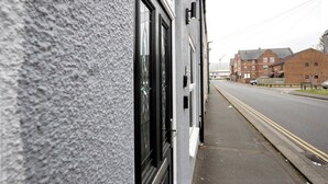 Straßenansicht eines Gebäudes mit großen Fenstern und einer strukturierten Fassade.