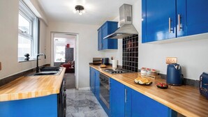 Eine moderne Küche mit blauen Schränken, einer Holz Arbeitsplatte und einer Edelstahl-Dunstabzugshaube.