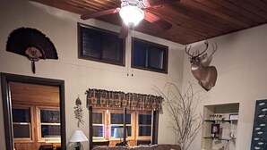 Ein gemütliches Wohnzimmer mit einem braunen Ledersofa, einem Holztisch und einem Deckenventilator.
