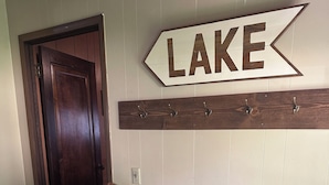 Ein Flur mit einer Holztür, einem Kleiderständer und einem Schild mit der Aufschrift 'LAKE'.