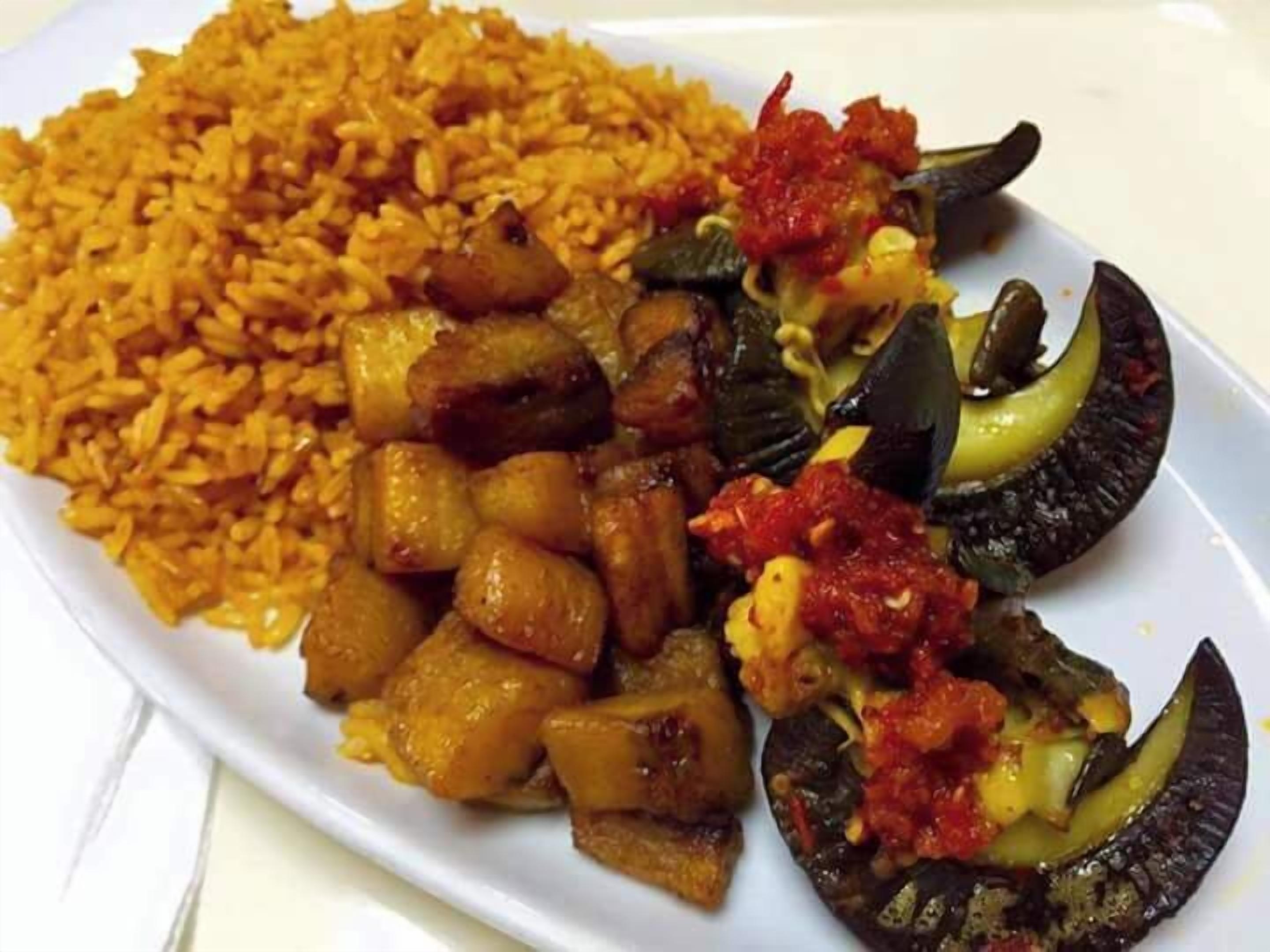 Ein Teller Essen mit Reis, Bratkartoffeln, gegrillter Aubergine und Tomatensoße.