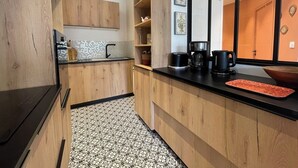 Een moderne keuken met houten kastjes, een zwart aanrecht en een vloer met een patroon.