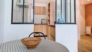Een moderne keuken met houten kastjes, een groot raam en een eethoek met een tafel met dessin en een houten kom.
