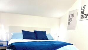 Une chambre à coucher avec un lit, une couvre-lit bleue et blanche, et un sol à motifs.