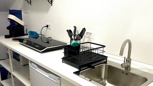Une cuisine moderne équipée d’un évier en acier inoxydable, d’une machine à café et d’un égouttoir à vaisselle.
