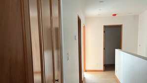 Un couloir avec des portes en bois et une rambarde blanche.