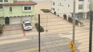 Une rue résidentielle bordée de maisons, avec une voiture garée et un panneau indiquant un passage piéton.