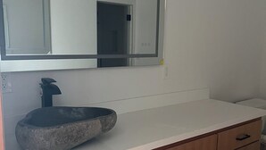 Une salle de bain avec un lavabo en pierre, des meubles en bois et un grand miroir.