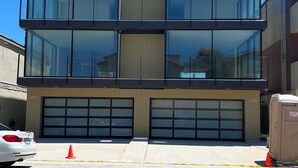 Un bâtiment moderne à deux étages, doté de grandes fenêtres en verre et d’une entrée de garage.