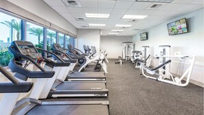 Une salle de sport équipée de tapis de course, de vélos elliptiques et de matériel de musculation.