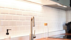 Een moderne keuken met een spoelbak van roestvrij staal, een houten aanrechtblad en een wit betegelde achterwand.