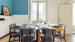 A dining area with a table set for four, chairs, and a window with a view of the mountains. - Eleganza in Centro a Cefalù by Wonderful Italy (Cefalù)