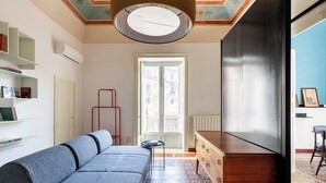 A modern living room with a sofa, a wooden dresser, and a red metal stand. - Eleganza in Centro a Cefalù by Wonderful Italy (Cefalù)
