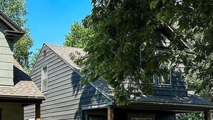 A two-story house with a gabled roof and a dormer window. - Experience KC from Twin Bells: Two Charming Bungalows, One Prime Location! (Kansas City)