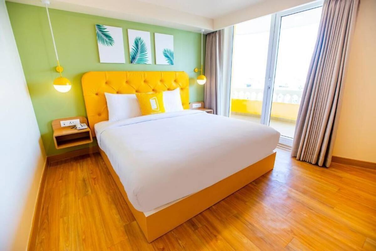 Una camera d'hotel con un letto grande, una parete verde e vista all'esterno.