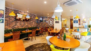 A restaurant with brick walls, yellow pendant lights, and a variety of seating options including booths and tables. - Bloom Hub - Guindy (Chennai)