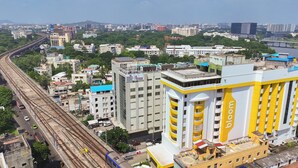 A high-rise building with a prominent yellow and white color scheme, featuring multiple balconies and a rooftop terrace. - Bloom Hub - Guindy (Chennai)